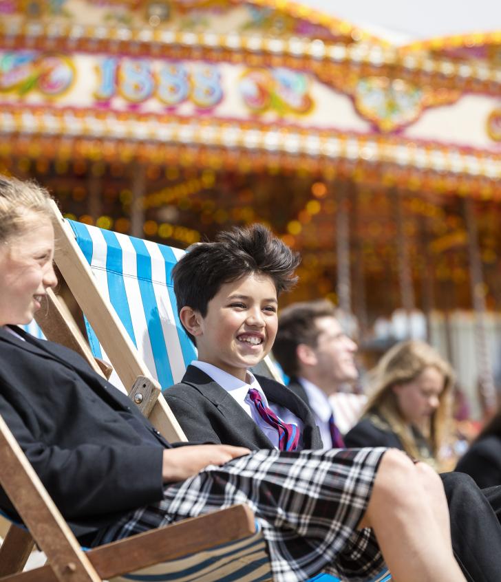  Pupils in their uniform sitting on Brighton Beach in deck chairs 