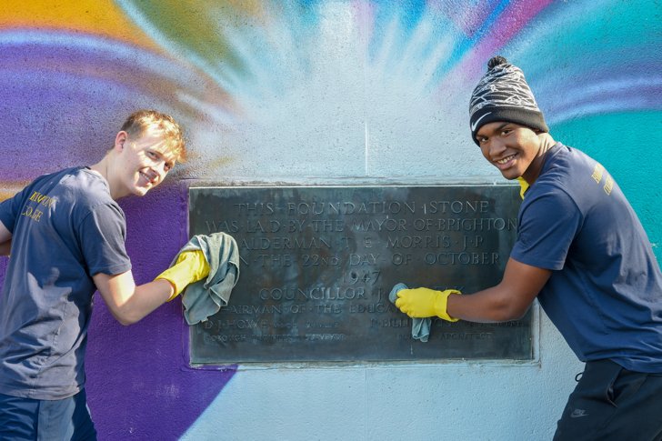  Pupils with cleaning gloves and cloths scrubbing a plaque on Make A Difference Day 