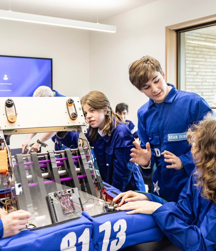  Pupils in blue boiler suits examining a piece of machinery in Robotics with Gear Zero 