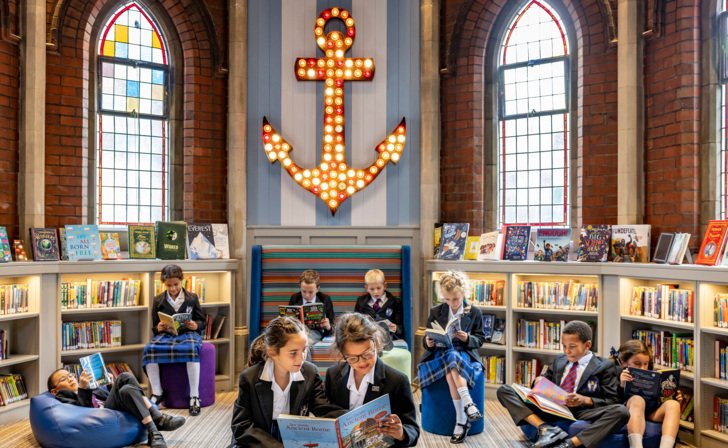  Prep School pupils sitting on beanbags in the library reading books amongst the book shelves 