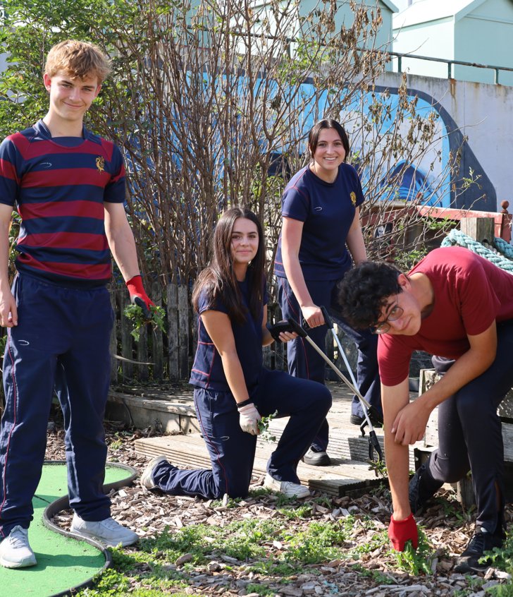  Pupils with gardening equipment pulling up weeds from the ground around Brighton on Make A Difference Day 