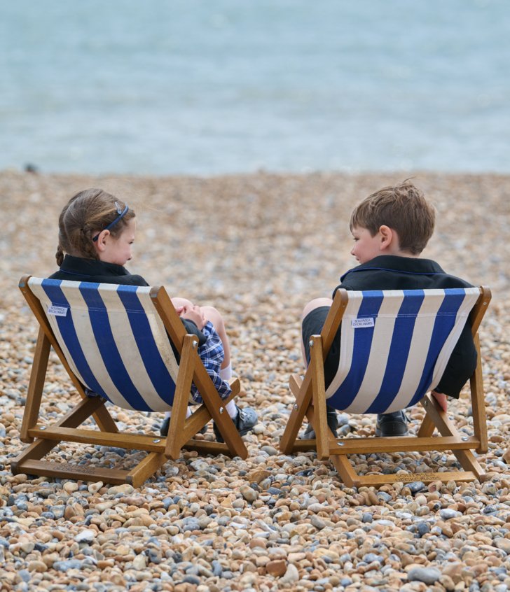  Pre-Prep pupils enjoying sitting together on deck chairs on the beach and looking at the sea 