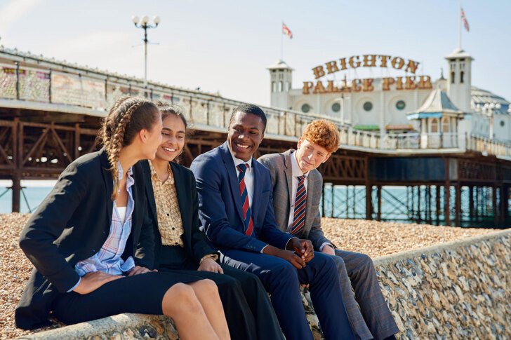  Sixth form pupils enjoying themselves on the beach in front of Brighton Pier 