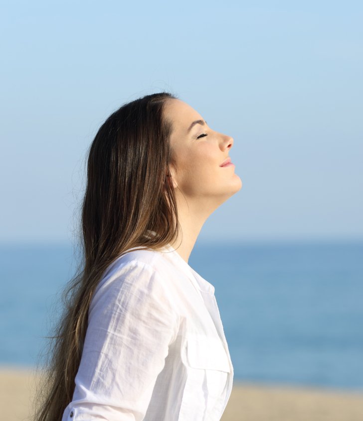  Person with their eyes closed enjoying being at peace standing on the beach 