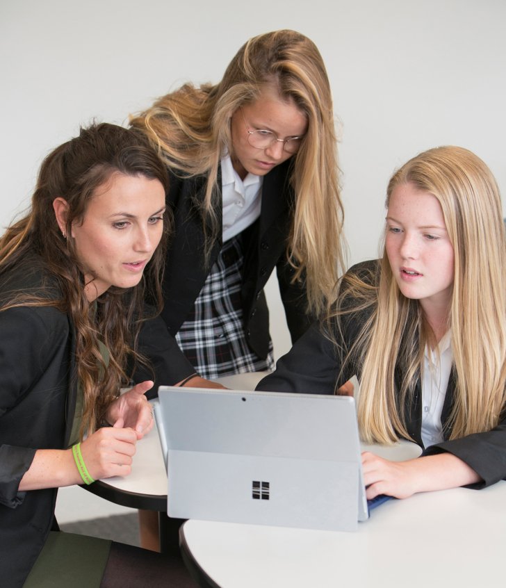  Fourth Form pupils and their teacher looking at a laptop together during a lesson 