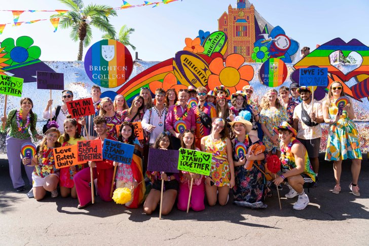  Brighton College pupils and staff enjoying celebrating Pride in front of the float holding posters 