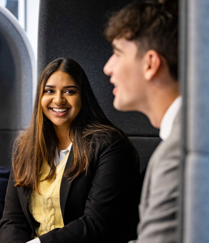  Sixth Form pupils in suits sitting in a booth and taking together in the Sixth Form Centre 