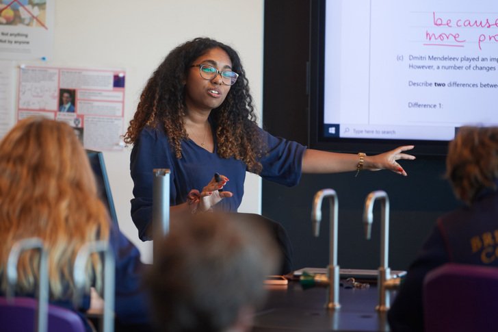  Teacher explaining the answer to questions on the board in a Chemistry lesson 