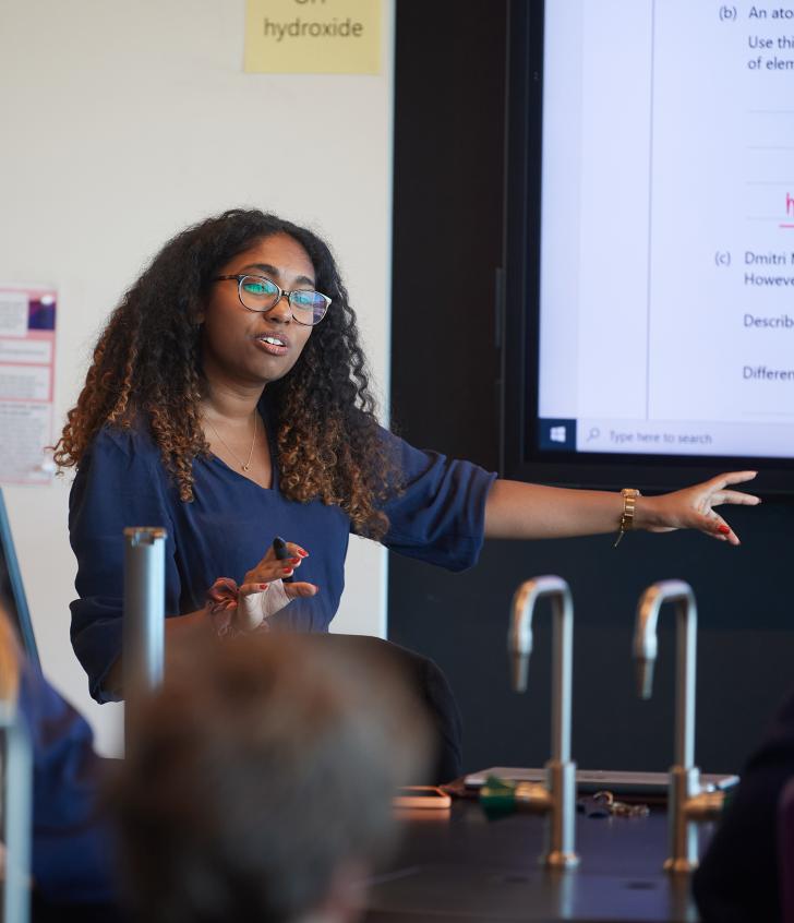  Teacher explaining the answer to questions on the board in a Chemistry lesson 