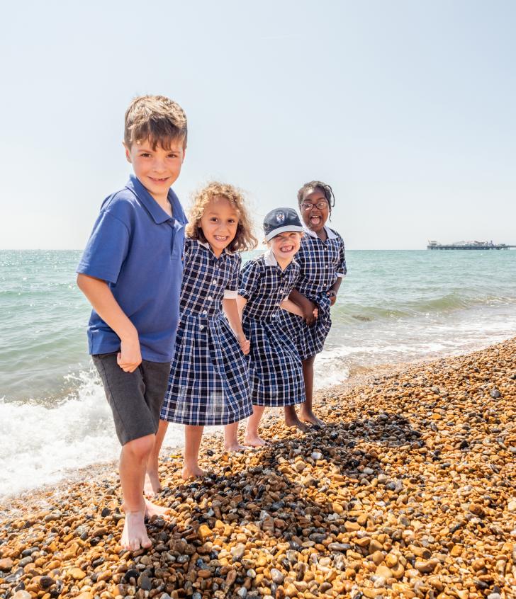  Pre-Prep pupils with barefeet playing in the sea and on the stones on the beach 