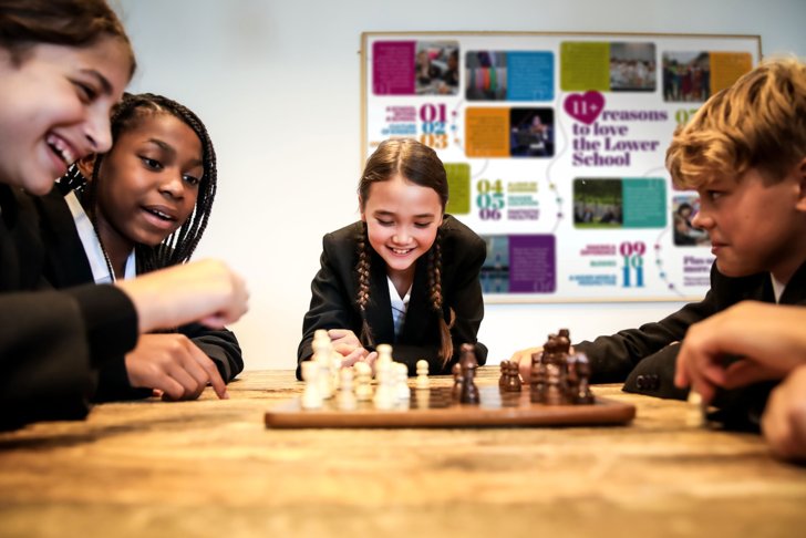  Lower School pupils sat at a table around a Chess board playing in their Common Room 