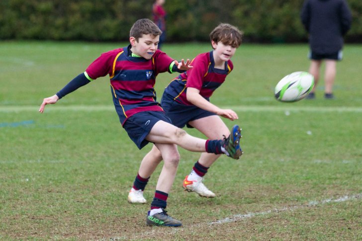  Prep School pupil kicking a rugby ball in a fixture against another school 