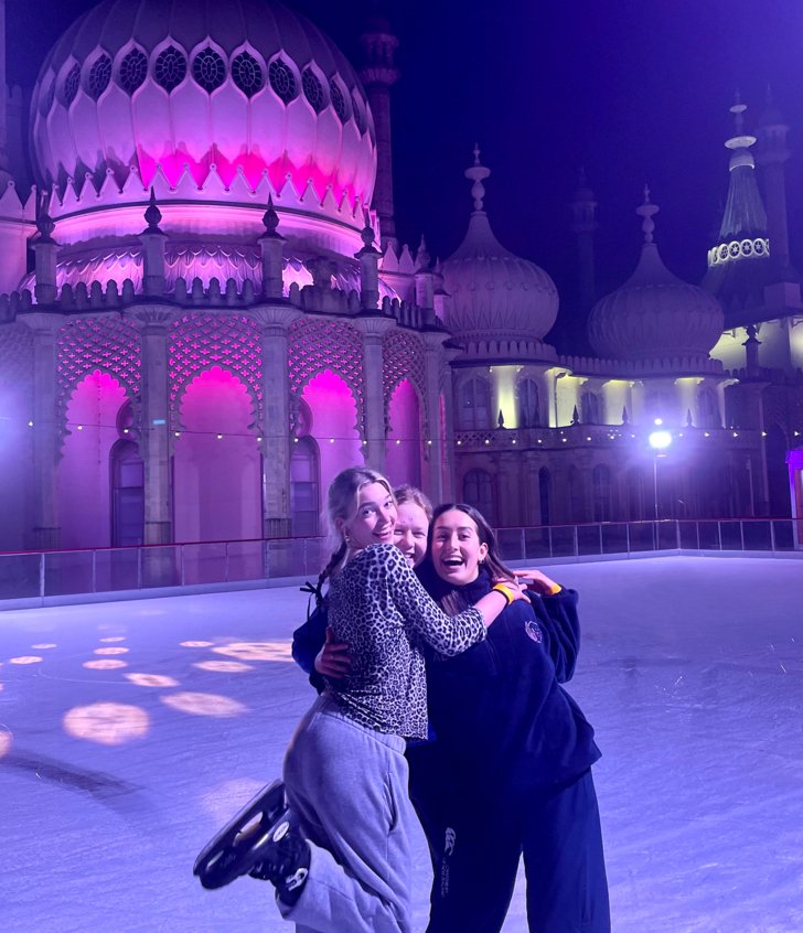  Boarders enjoying Ice Skating at Brighton Pavilion with their arms around each other 