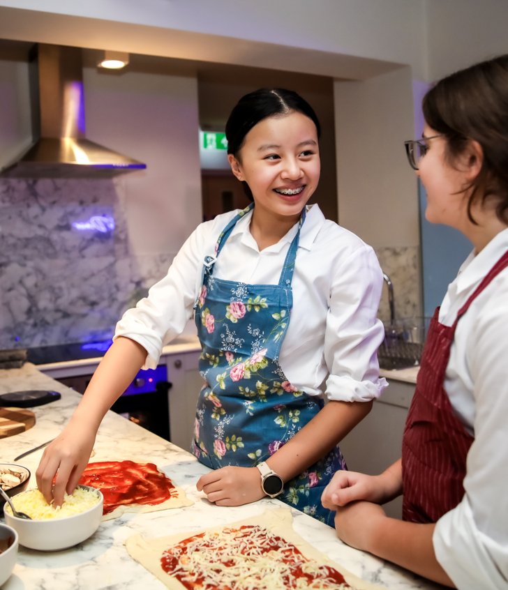  Boarders making homemade pizzas together in the evening in the kitchen in their Boarding house 