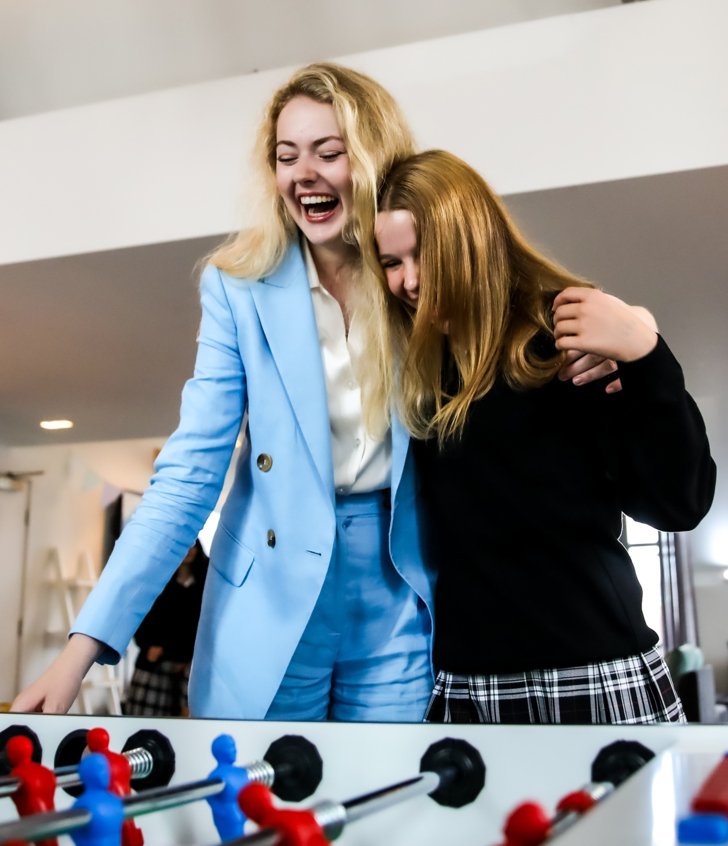  Boarding pupils in New House Common Room with their arms around each other and playing table football 