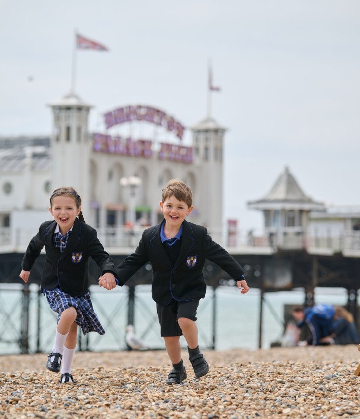  Pre-Prep pupils running along the stones on the beach in front of Brighton Pier 