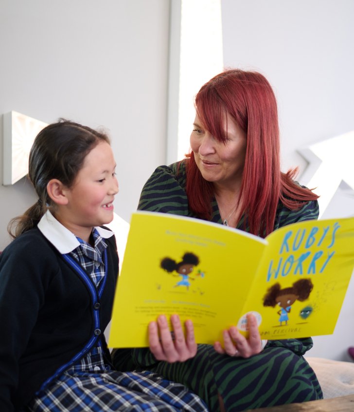  Pre-Prep pupil sitting with their teacher reading the book 'Ruby's Worry' together 