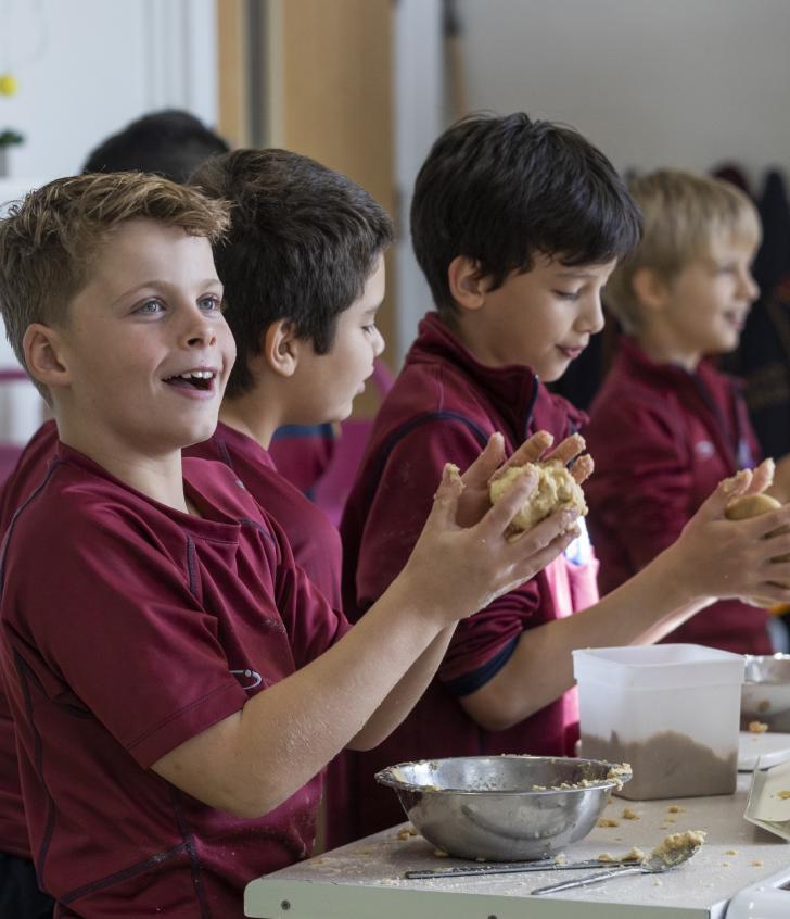  Pupils rolling dough between their hands and enjoying baking 