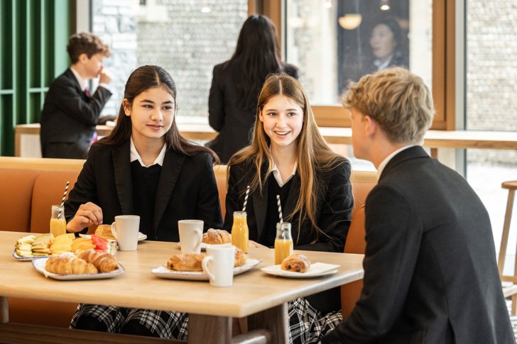  Pupils sitting in Scott's Café enjoying orange juice and pastries whilst chatting 