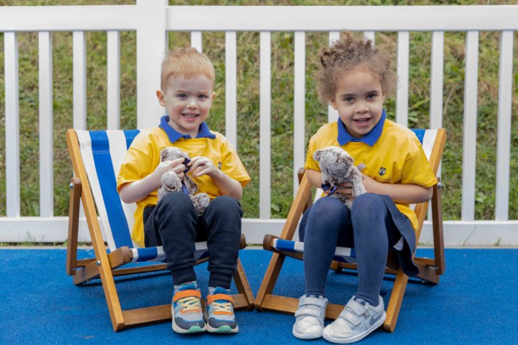  Pufflings sitting in deck chairs holding teddy bears in the playground 