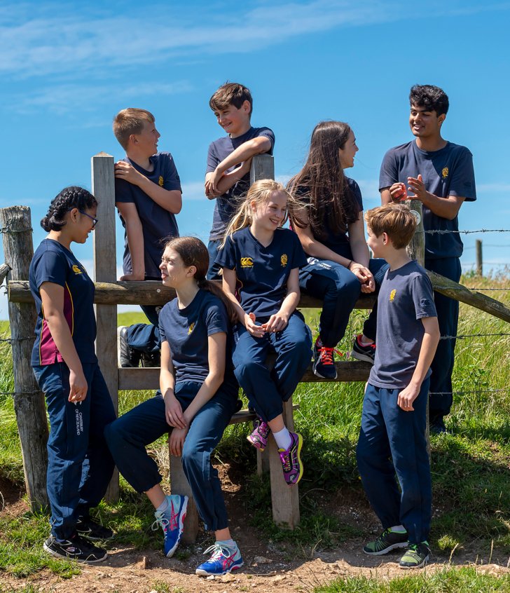  Pupils in Games Kit sitting on a gate on the South Downs Way in the sunshine 