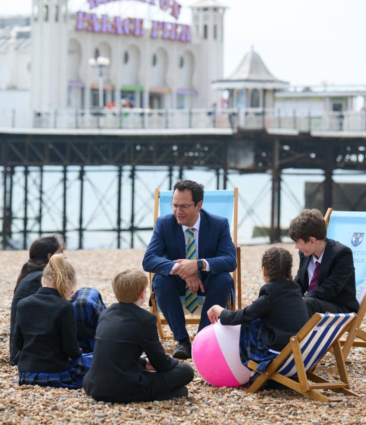  Pre-Prep and Prep School pupils sitting on the beach in front of the Pier with Ant Falkus 