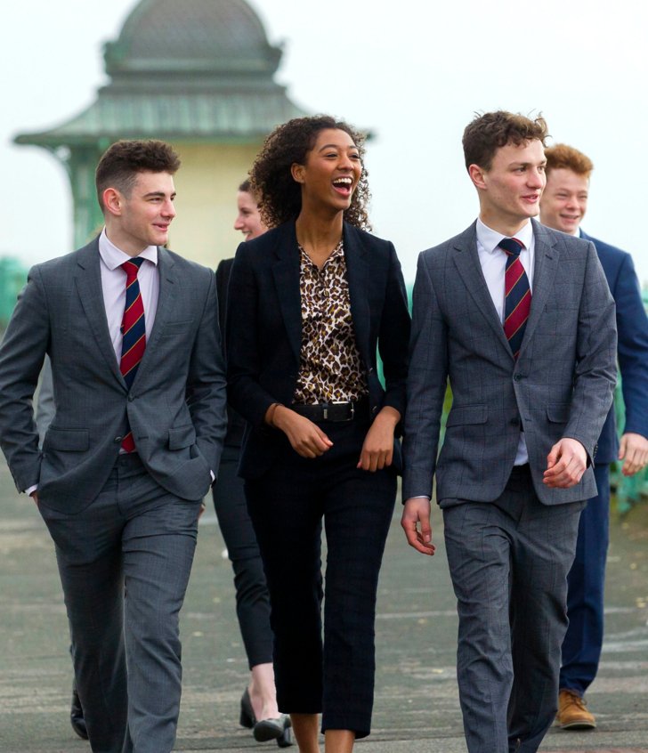  Sixth Form pupils in suits walking and talking together on Brighton seafront 