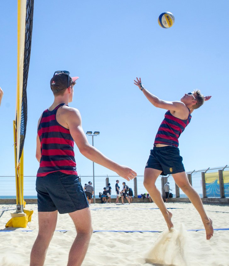  Pupil jumping up to spike a ball by the net at a Volleyball match at Yellowave 