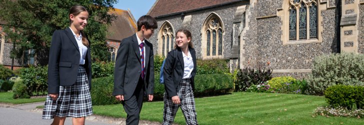  Pupils in uniform talking to each other whilst walking through the Quad outside the Chapel 