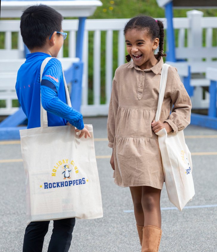  Pupils excited to see each other in the playground and holding their Rockhoppers tote bags 