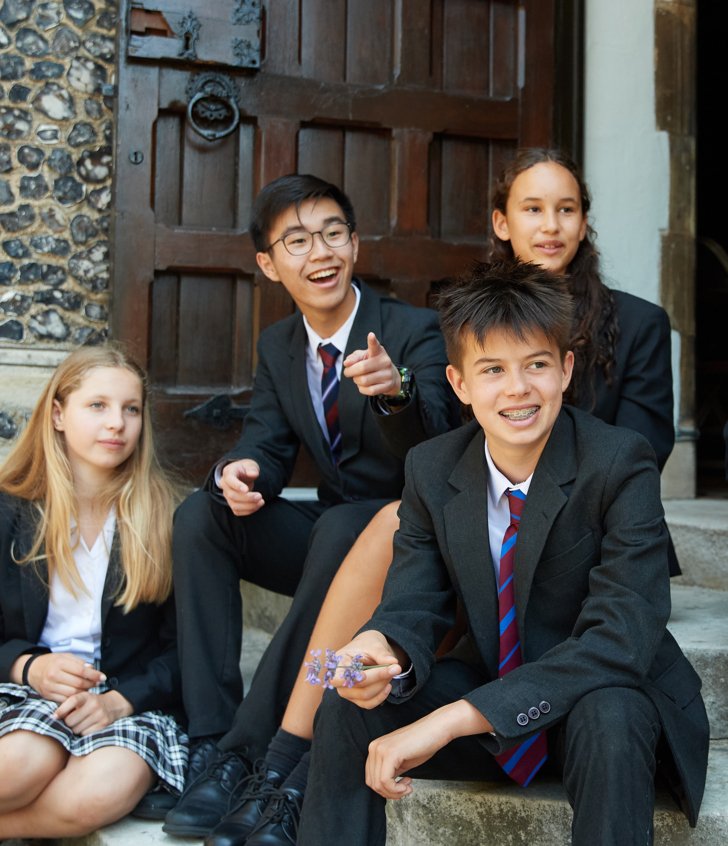  Pupils sitting on the steps of the Chapel together looking at something in the distance 