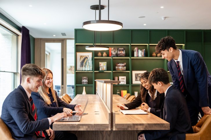  Pupils sitting at the tables with laptops and notebooks studying in the Sixth Form Club 