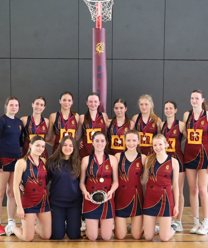  Winners of the ISNC Plate with their trophy and medals in front of a netball post 