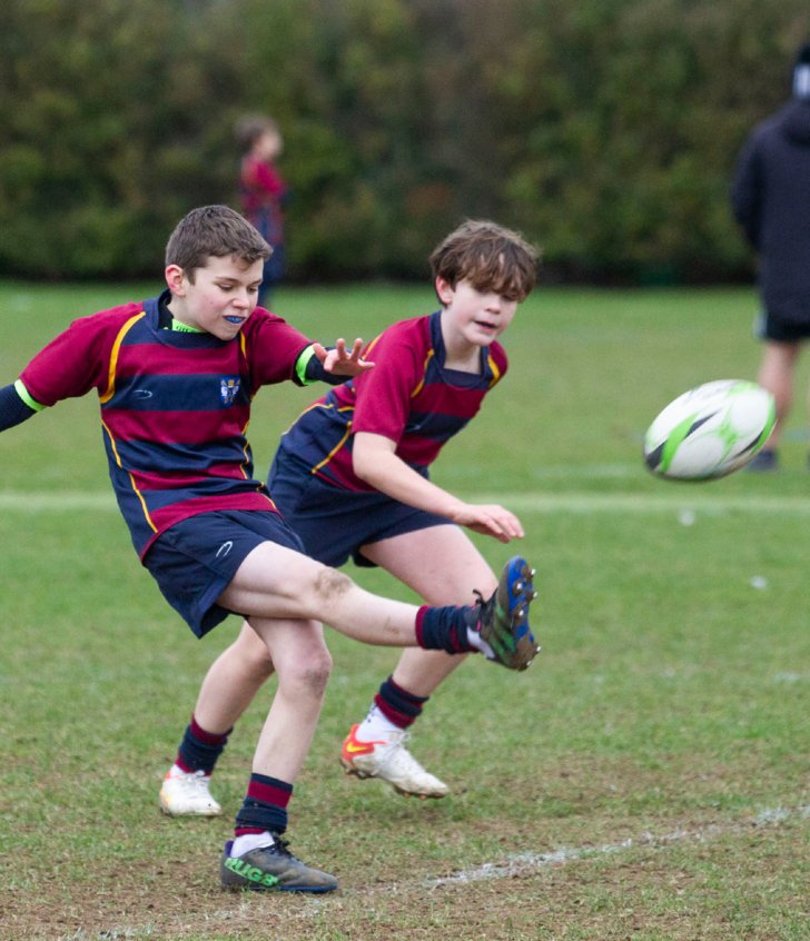  Prep School pupil kicking a rugby ball in a fixture against another school 