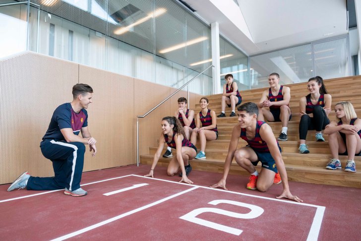  Pupils sitting on the steps whilst others ready to run on Indoor Athletics Track with Director of Sport 