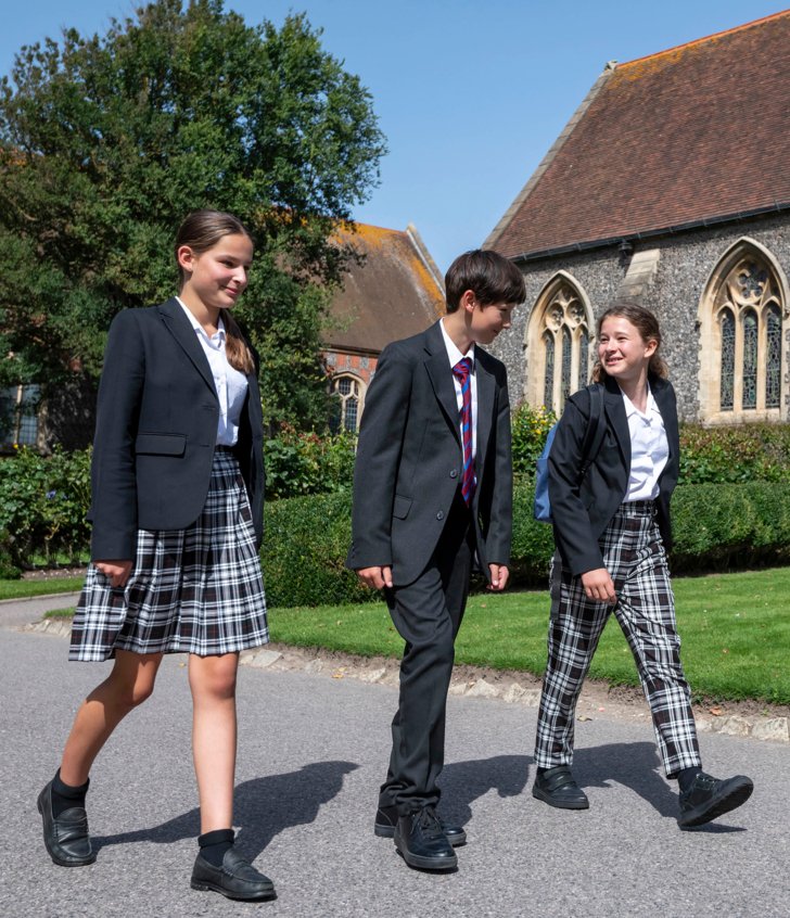  Pupils in uniform talking to each other whilst walking through the Quad outside the Chapel 