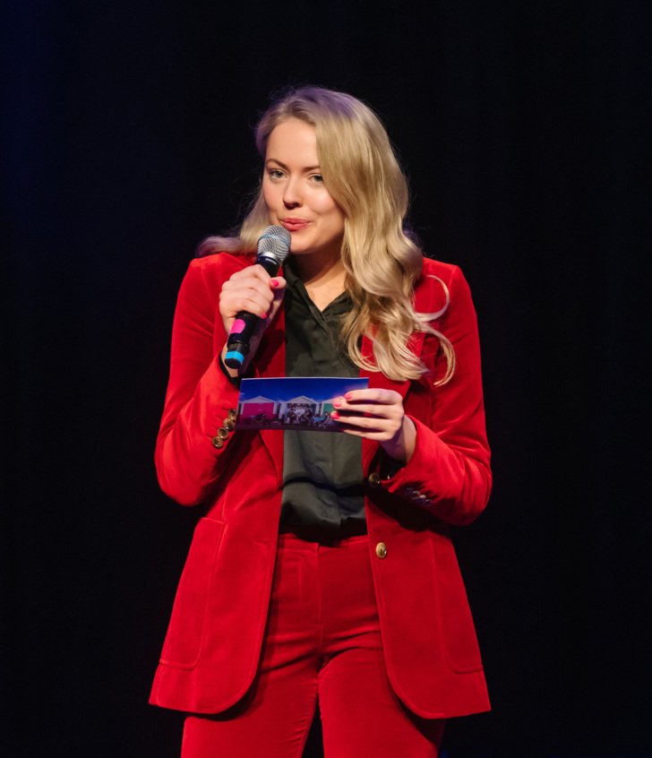  Upper Sixth pupil in a suit with cue card and microphone addressing the audience 