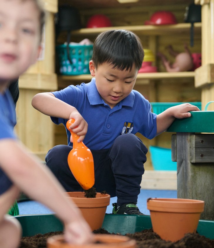  Nursery pupils putting soil into plants pots to grow plants 