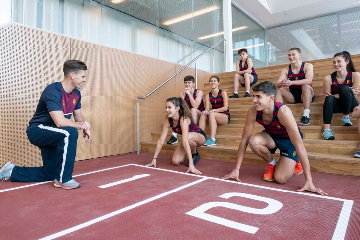  Pupils sitting on the steps whilst others ready to run on Indoor Athletics Track with Director of Sport 