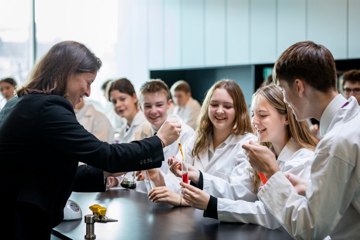  Pupil holding a test tube that the Biology teacher is adding a substance to as part of a Biology experiment 