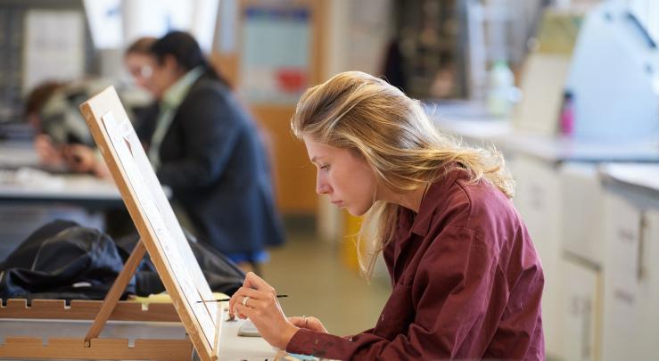  Pupil painting an A-Level coursework piece onto a canvas in the Art Room 