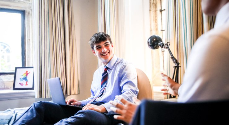  Sixth Form pupil sitting with their laptop and enjoying chatting in their room after school 