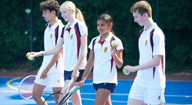  Pupils holding rackets and balls and walking down the Tennis Court 