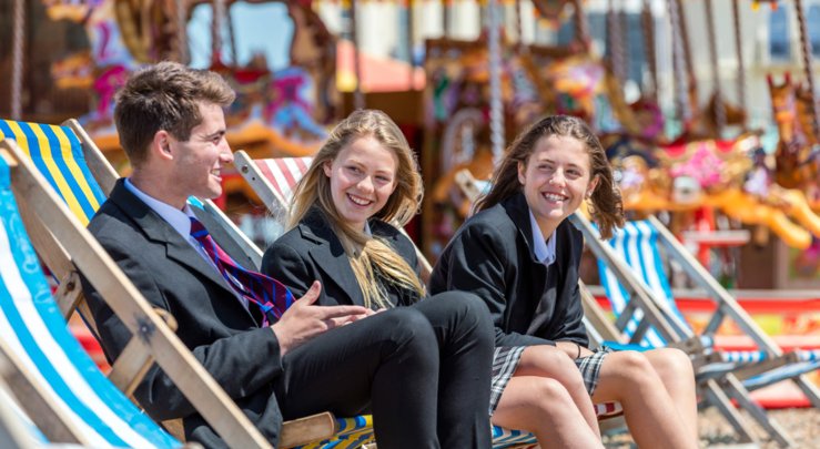  Pupils in their uniform sitting on Brighton Beach in deck chairs 