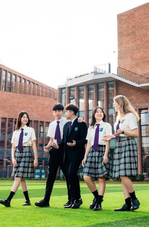  Pupils in uniform walking outside on the grass at Brighton College Vietnam 