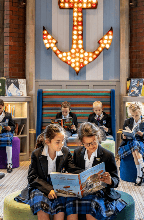  Prep School pupils sitting in the Library reading books together on the seats 